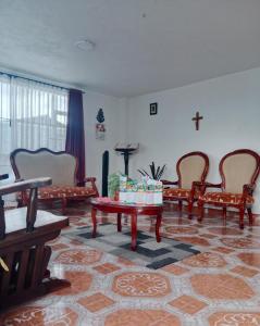 a living room with chairs and a table and a cross on the wall at Cabaña Rural BlueHousePaipa in Paipa