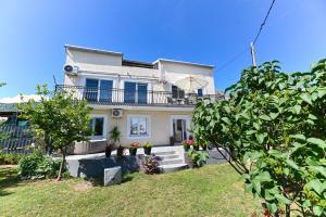 a white house with a balcony and a yard at Apartmani Dolores in Kaštela