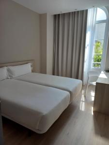 フィゲイラ・ダ・フォズにあるB&B HOTEL Figueira Da Fozのベッドルーム(大きな白いベッド1台、窓付)