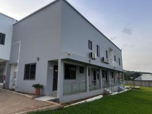 a white building with a balcony on the side of it at Krotia Lodge Atimpoku in Atimpoko