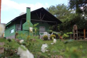 a green house with two white chairs in the yard at Casitas de Campo Wara kusi in Vaqueros