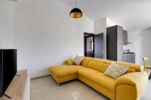 a yellow couch in a living room with a kitchen at Mandarin Apartment 5 in Àrbatax +19 photos