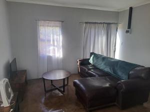 a living room with a leather couch and a table at 22 Duvenhage in Postmasburg
