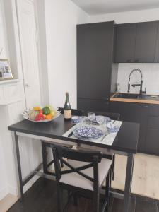 a kitchen with a table with a bowl of fruit and a sink at Appartement EMILiA Centre ville in Vitré