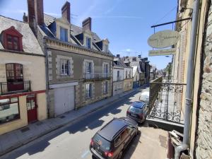 two cars parked on a city street with buildings at Appartement EMILiA Centre ville in Vitré