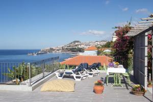 d'un balcon avec des chaises et des tables offrant une vue sur l'océan. dans l'établissement Irlandas Villa Funchal Seaside Villas, à Funchal