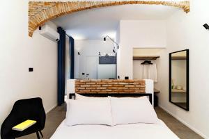 a bedroom with a white bed and a black chair at Guesthouse Linaio - The House Of Travelers in Como