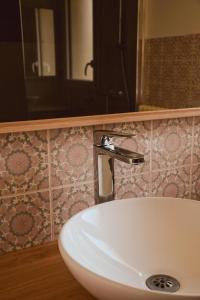 a bathroom sink with a faucet on a tiled wall at -LES LUTINS- Charmante maison les pieds dans l eau in Concarneau