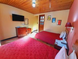 a bedroom with a red bed and a flat screen tv at Hotel y Restaurante Villa Esmeralda in Quetzaltenango