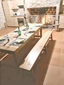 einen langen Holztisch in einem Zimmer mit Kamin in der Unterkunft Maison de 2 chambres avec jardin amenage et wifi a Chaumeil in Chaumeil