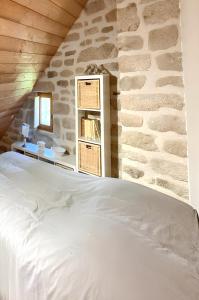 Bett in einem Zimmer mit einer Steinmauer in der Unterkunft Maison de 2 chambres avec jardin amenage et wifi a Chaumeil in Chaumeil