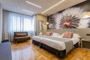 una habitación de hotel con una cama grande y una silla en Hostal Rodas Pamplona, en Pamplona
