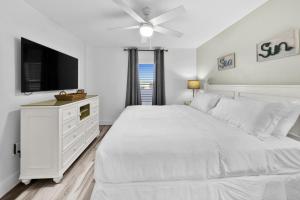 una camera bianca con letto bianco e TV a schermo piatto di Beautiful Updated Pelican Beach Unit!!! a Destin Altre 36 foto