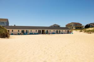 ein Gebäude am Strand neben einem Sandstrand in der Unterkunft Dolphin Oceanfront Motel - Nags Head in Nags Head