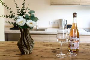 a table with a vase and a bottle of wine and two glasses at Ogre City Apartments in Ogre +3 photos