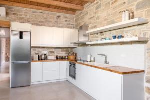 - une cuisine avec des placards blancs et un mur en pierre dans l'établissement Nature Villa Yasemi, à Kamilárion