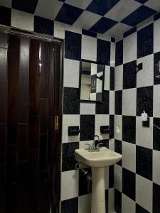 a bathroom with a sink and black and white tiled walls at Alborada 2 Cerca del Aeropuerto in Mexico City