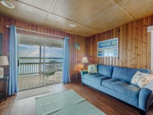 a living room with a blue couch and a balcony at Seahorse Sound in Topsail Beach