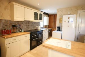 a kitchen with white cabinets and a white refrigerator at Tigh N Eilean Self Catering Aberfeldy in Aberfeldy