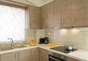 een keuken met houten kasten, een wastafel en een raam bij Sunny Apartment Lefkada - Lefkada BnB in Lefkada