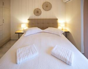 een wit bed met twee witte kussens erop bij Sunny Apartment Lefkada - Lefkada BnB in Lefkada +21 foto's