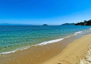 a beach with the ocean and mountains in the background at Thalassa Beach Kavala in Paleo Tsifliki