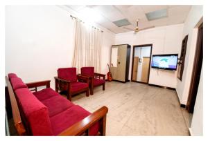 sala de estar con sillas rojas y TV en HAPPY HOMES, en Mangalore