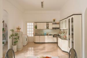 a large kitchen with white cabinets and a table and chairs at Oliu Home Đà Lạt in Xuan An