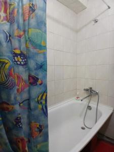 a bath tub with a shower curtain with fishes on it at Квартира на Дегтярёвской in Kyiv