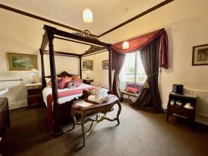 a bedroom with a large canopy bed with a table at Calthwaite Hall Bed & Breakfast in Penrith