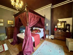 a bedroom with a canopy bed with red curtains at Calthwaite Hall Bed & Breakfast in Penrith