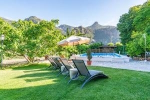 eine Gruppe von Stühlen mit einem Sonnenschirm und einem Pool in der Unterkunft Casa Rural Olivillas Garden-Sierra Nevada in Güéjar-Sierra