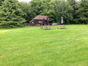 twee picknicktafels in een veld met een schuur bij WoodLands Basic Bell Tent 3 in Grantham