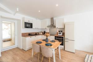 a kitchen with a wooden table and a kitchen with white cabinets at Charmante maison neuve avec terrasse Port du Legue in Plérin