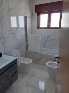 a white bathroom with a toilet and a sink at Casa Ferradal in Quintanilha +4 photos