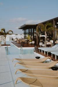 - une piscine avec des chaises et des tables dans un bâtiment dans l'établissement Aguas de Ibiza Grand Luxe Hotel - Small Luxury Hotel of the World, à Santa Eulària des Riu
