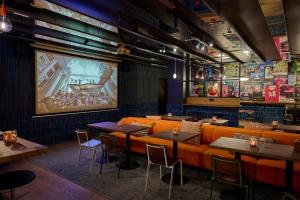 un restaurant avec des sièges orange et un grand écran dans l'établissement Generator Berlin Alexanderplatz, à Berlin