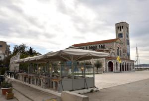 a building with an umbrella in front of a church at Eugenia's Luxury Apart in Volos