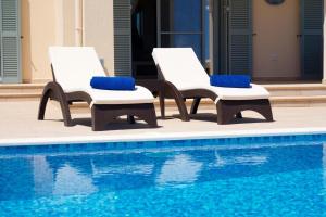 two lounge chairs next to a swimming pool at Villa Aglaia in Mavrata in Mavráta