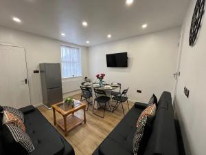 a living room with a black couch and a table at Florence House - 3 Twin Bedroom House 3 Showers 2 Ensuites Plus Walk-in Wetroom Garden Fast Wi-Fi J1-M5 on Doorstep Weekly Stays ok Contractor Accommodation Another Best-in-Class in West Bromwich