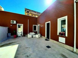 een rood gebouw met een patio met witte meubels bij SoleMare Alloggio Turistico in Marsala