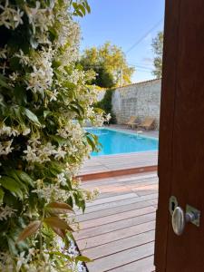 a view of a swimming pool from a door with flowers at LE DOMAINE DE FERRAT in Mirambeau
