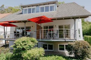 ein Haus mit zwei roten Sonnenschirmen auf einem Balkon in der Unterkunft Ferienhaus Emil in Meersburg