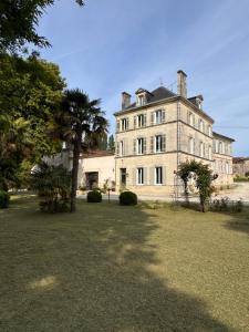 a large building with a palm tree in front of it at LE DOMAINE DE FERRAT in Mirambeau