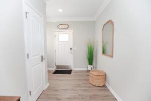 einen Flur mit einer weißen Tür und einem Spiegel in der Unterkunft Sojourn Palm Tree Family Oasis 4 BR in North Camellia Acres