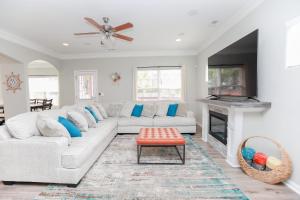 ein Wohnzimmer mit einer weißen Couch und einem Kamin in der Unterkunft Sojourn Palm Tree Family Oasis 4 BR in North Camellia Acres