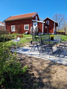 コールモーデンにあるKolmårdstorpet Blomsätterの赤い納屋の前にテーブルと椅子のあるパティオ