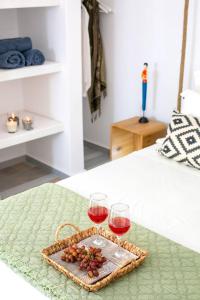 two glasses of wine and a tray of grapes on a bed at Elite Houses Santorini in Emporio Santorini
