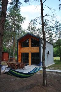 a hammock in front of a cabin in the woods at Domki SHERWOOD in Gawłowo