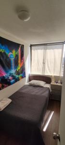 a bedroom with a bed and a painting on the wall at Departamento Parque O'Higgins in Santiago